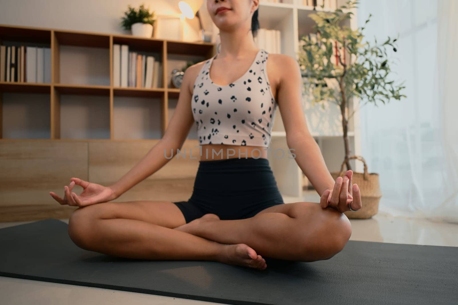 Focused female practicing mindfulness and breathing exercises during home yoga session.