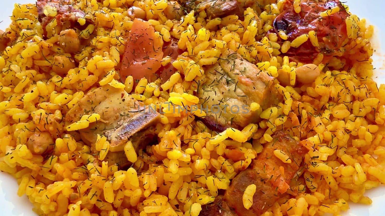 A visually appealing plate of spiced rice with succulent meat pieces and colorful, fresh vegetables