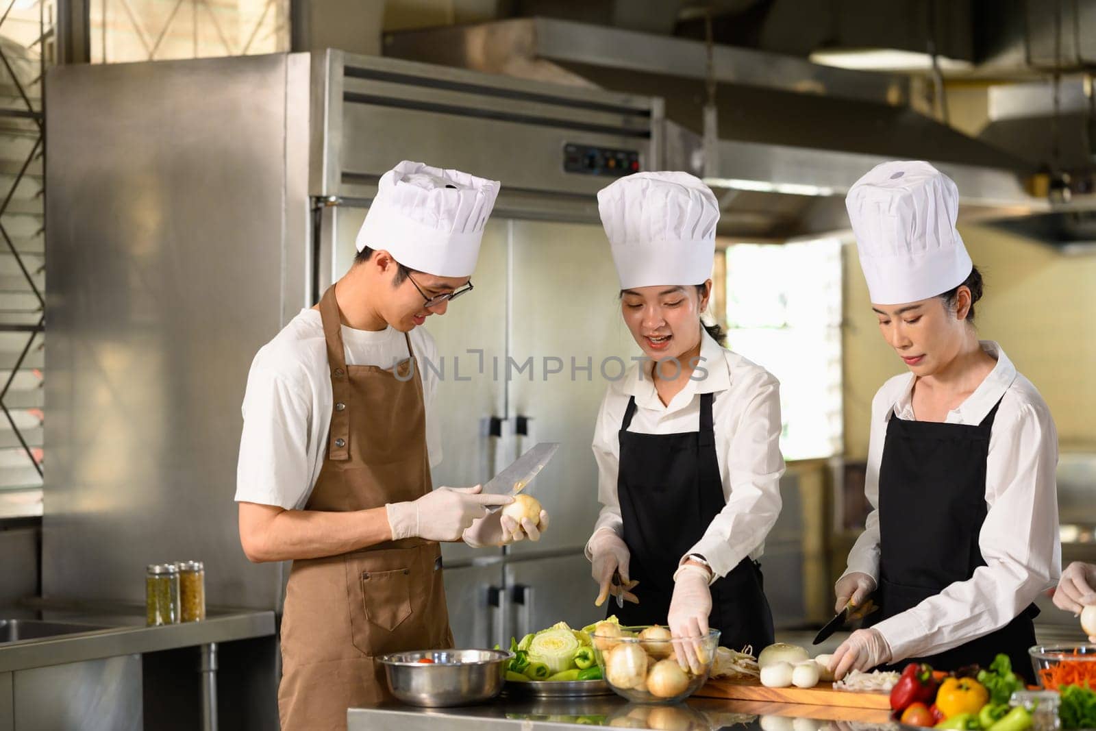 Group of cooking school students preparing fresh vegetables during a culinary class.
