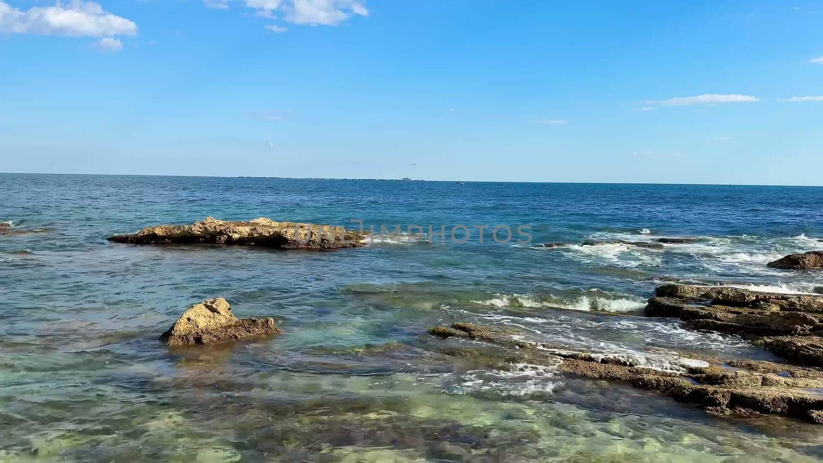 This striking and tranquil seaside scene beautifully showcases rocky formations along with the crystalclear waters