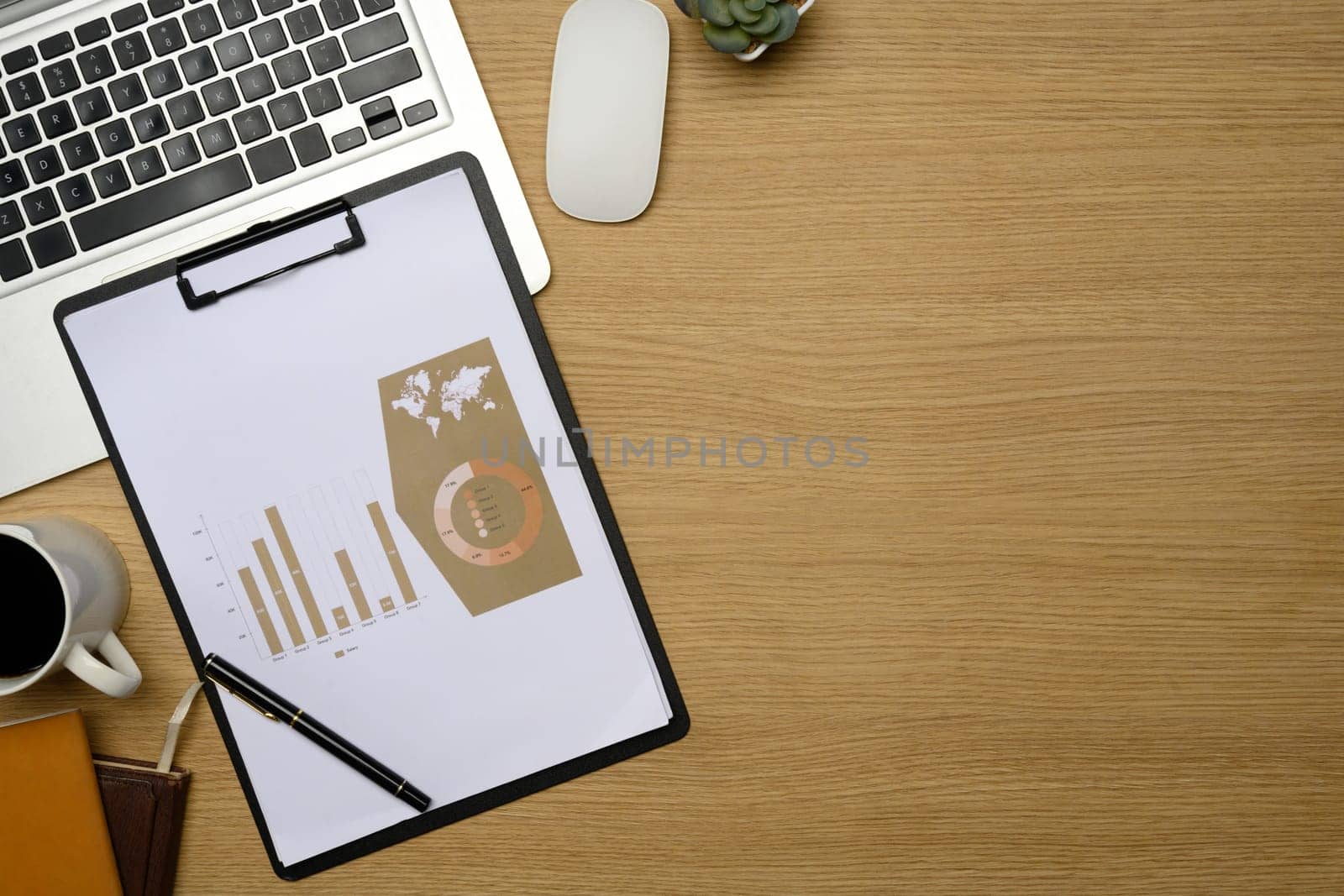 Office desk with analytics reports, cup of coffee and laptop.