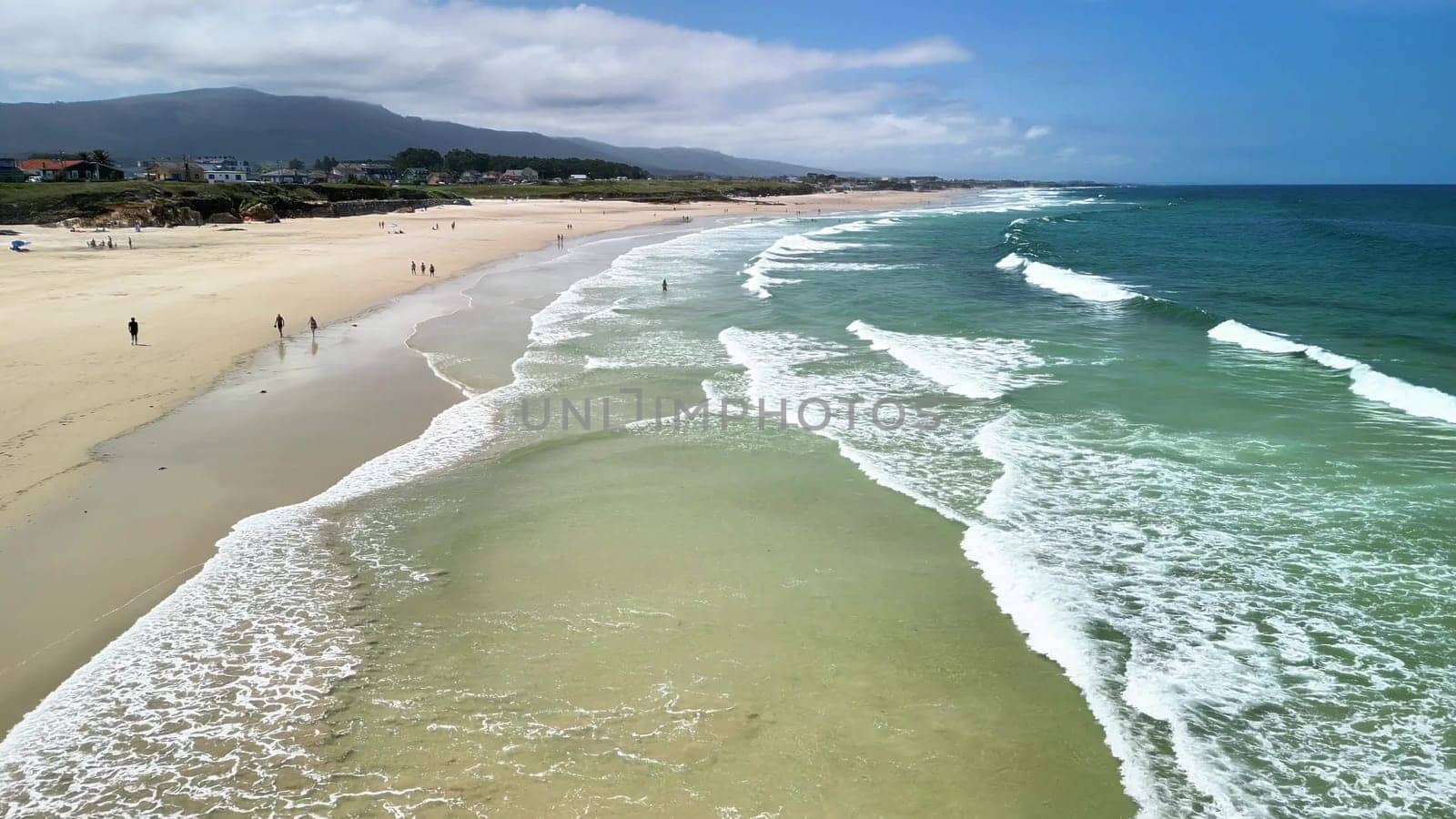 Enjoy a stunning and breathtaking aerial view of a serene beach featuring gentle waves and soft golden sand