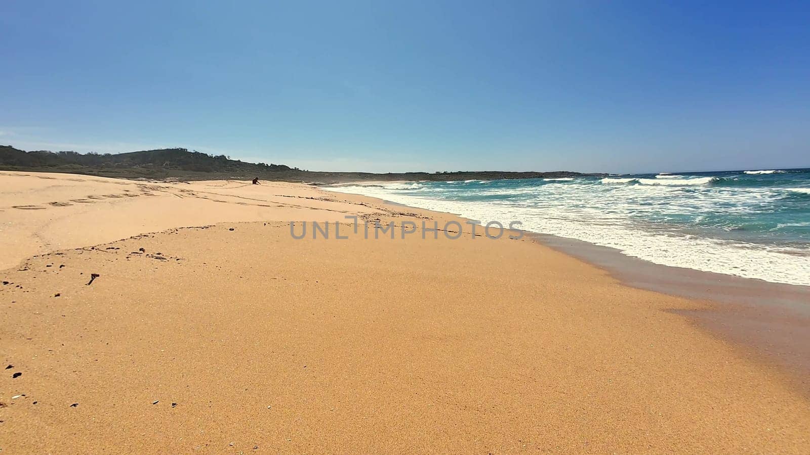 Breathtaking view of a sandy beach under a clear blue sky, perfect for relaxing and enjoying nature.