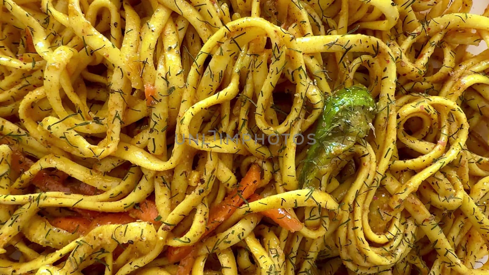 A colorful plate of stirfried noodles seasoned with aromatic herbs and fresh, flavorful seasonal vegetables
