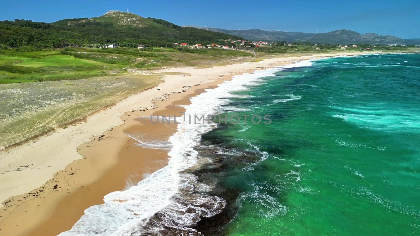 An aerial shot beautifully showcases the stunning clear waves and sandy beaches along the picturesque coast