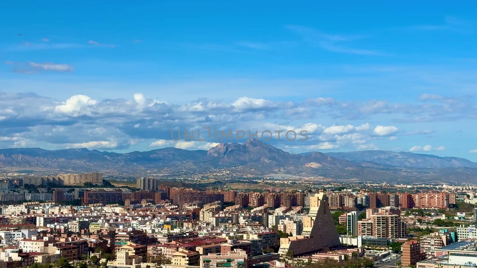 The city skyline is vibrant, showcasing majestic mountains under a bright blue sky, perfect for urban themes