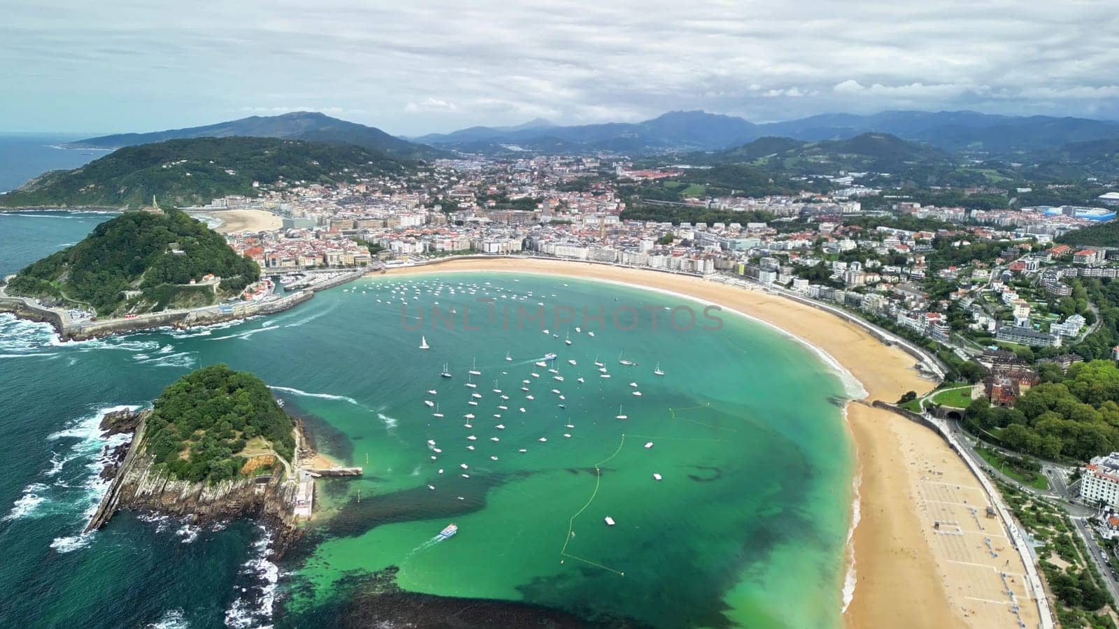 This aerial landscape showcases a stunning beach, vibrant blue water, and a quaint coastal town nearby
