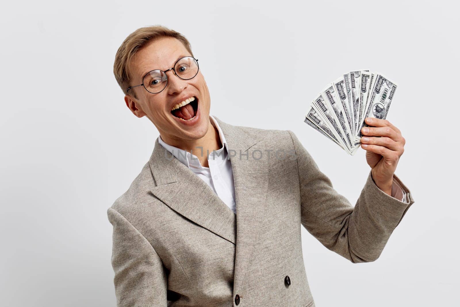 excited young caucasian man wear beige plaid jacket hold us dollar bills smiling celebrating financial success freelance income online work digital nomad lifestyle concept of freelancing and remote work