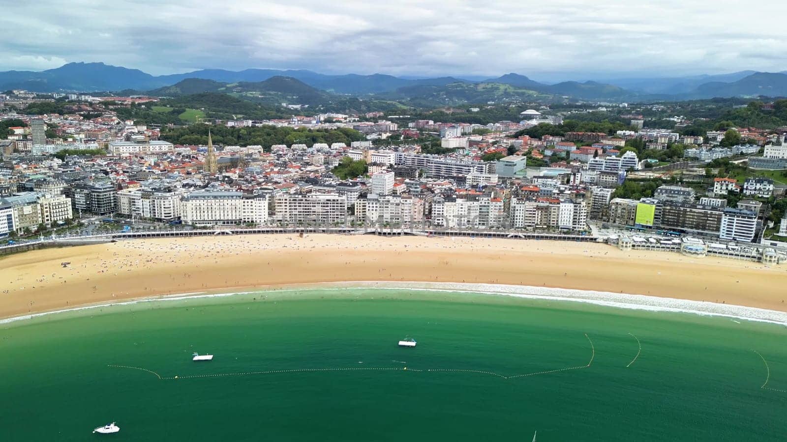 A stunning aerial shot beautifully depicts a picturesque beach nestled next to a lively, vibrant coastal town