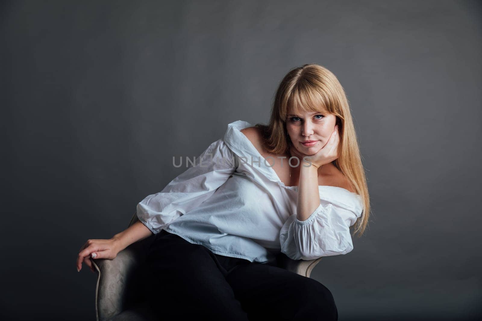 Portrait of a beautiful blonde young woman on a gray fashion background