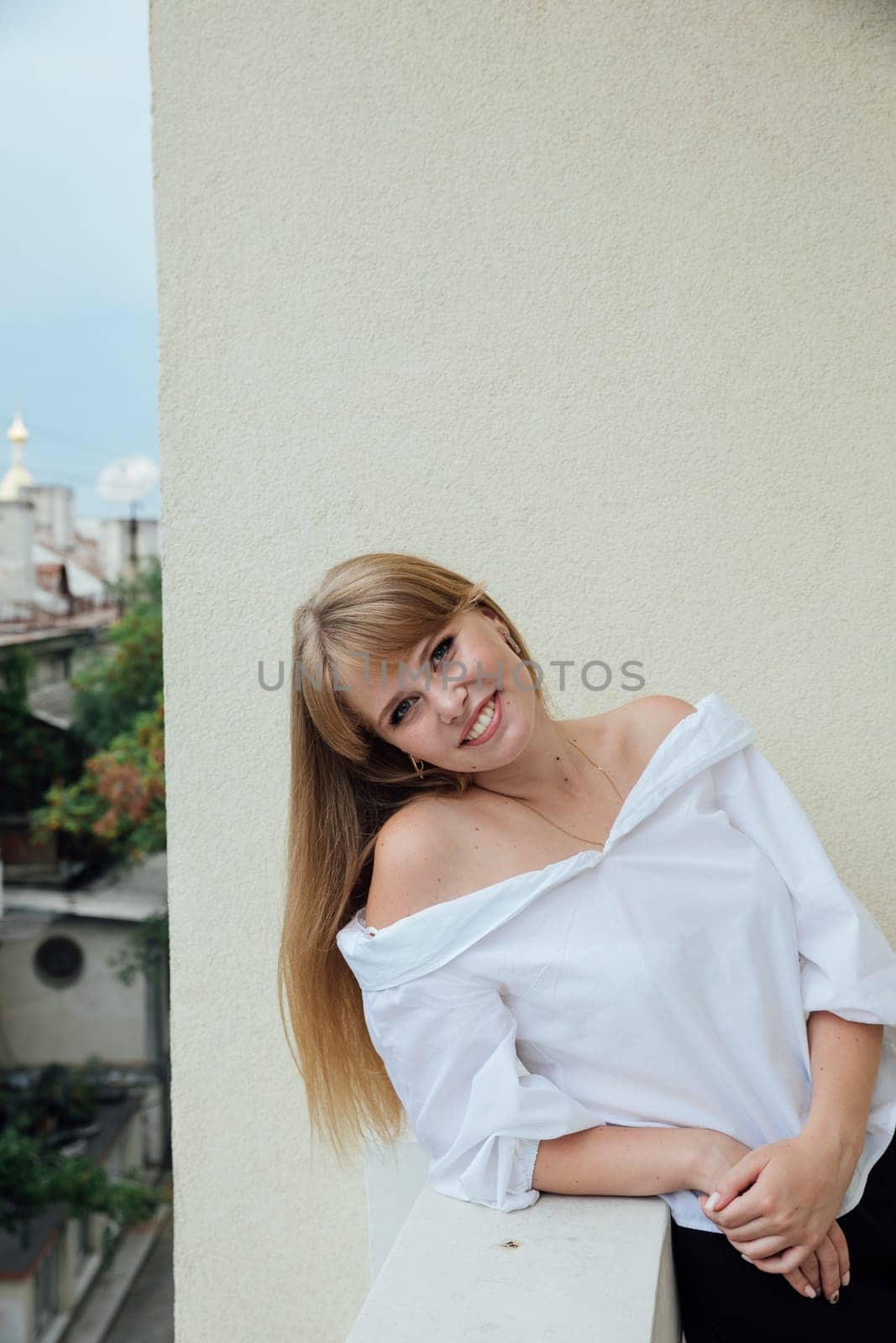 Young woman standing on the balcony on the street and smiling