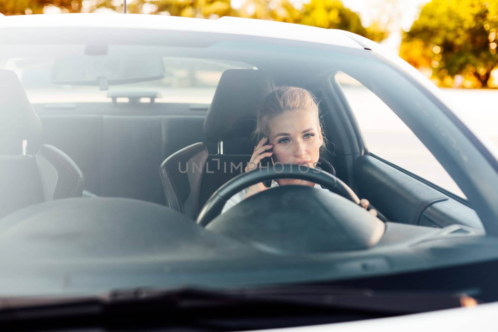 Woman blonde driver talking on the phone while driving a car