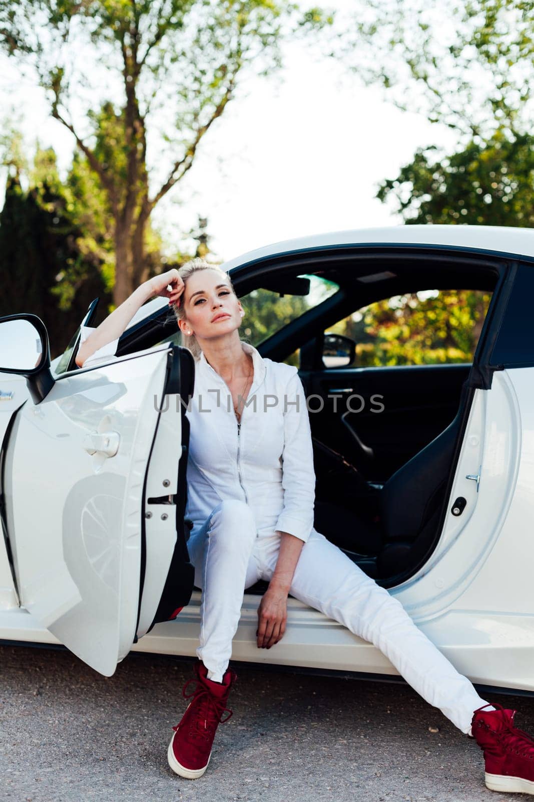 Woman blonde driver driving a white sports car on the road
