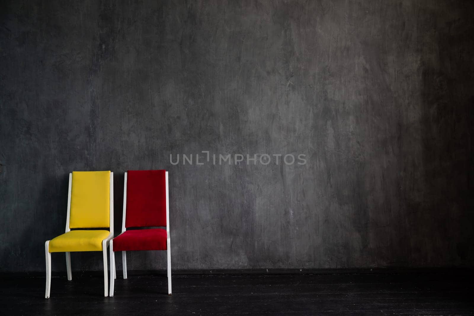 Two old chairs red and yellow in the interior of a gray room