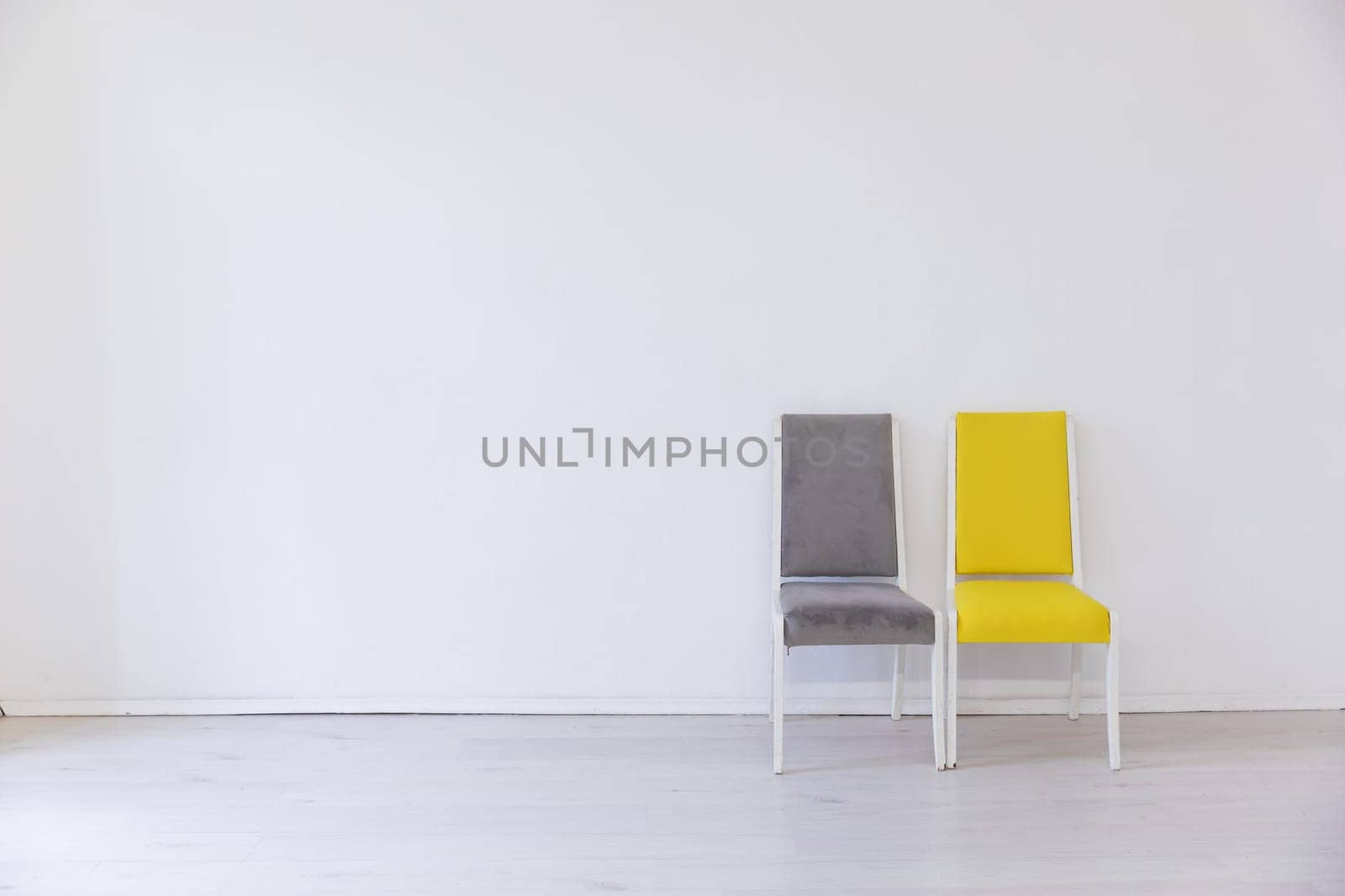 Two old chairs gray and yellow in the interior of a white room