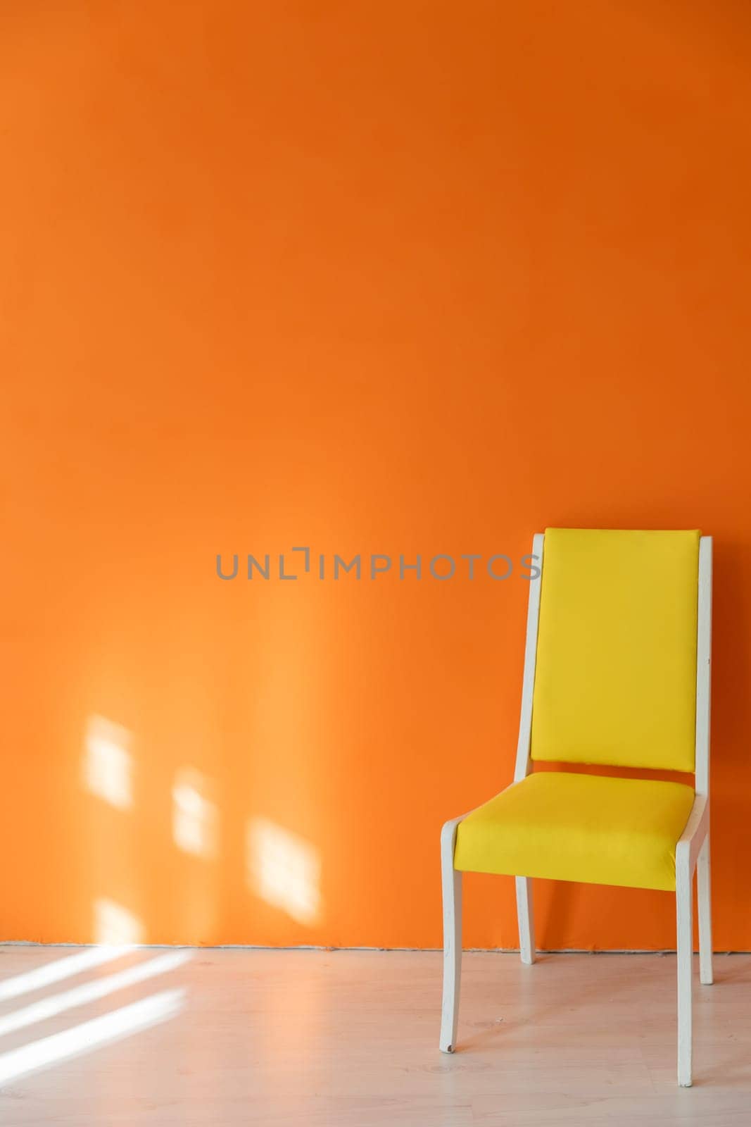 One old yellow chair against an orange wall