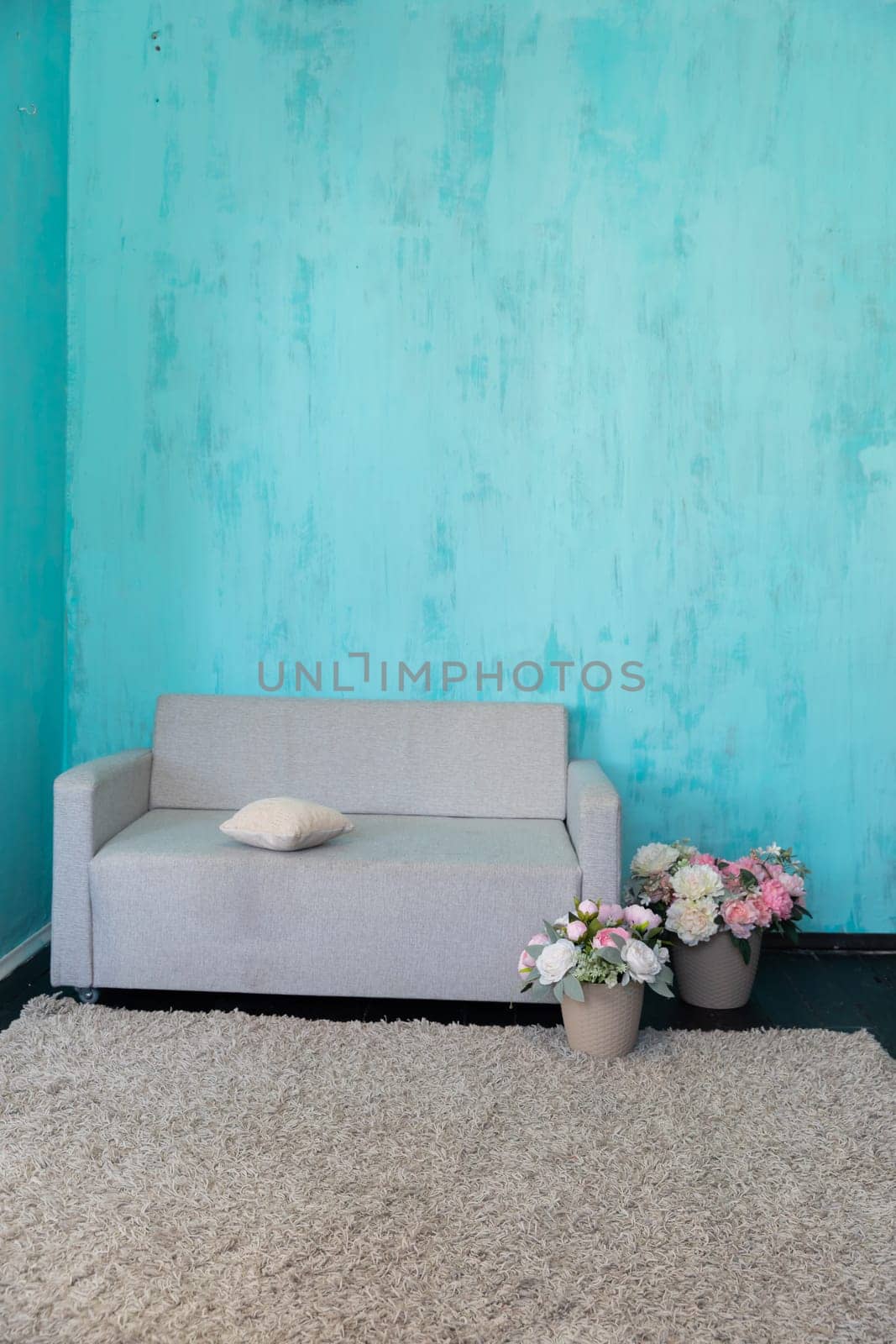 Gray office sofa with a vase of flowers in the interior of a blue room
