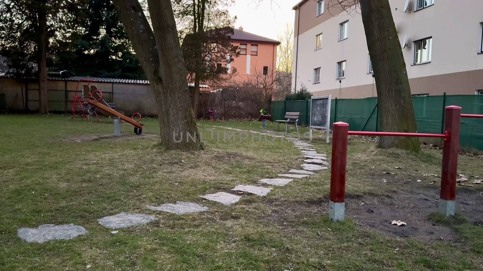 A calming and serene playground scene shows a lovely pathway, tall trees, and a cozy, enchanting sunset ambiance