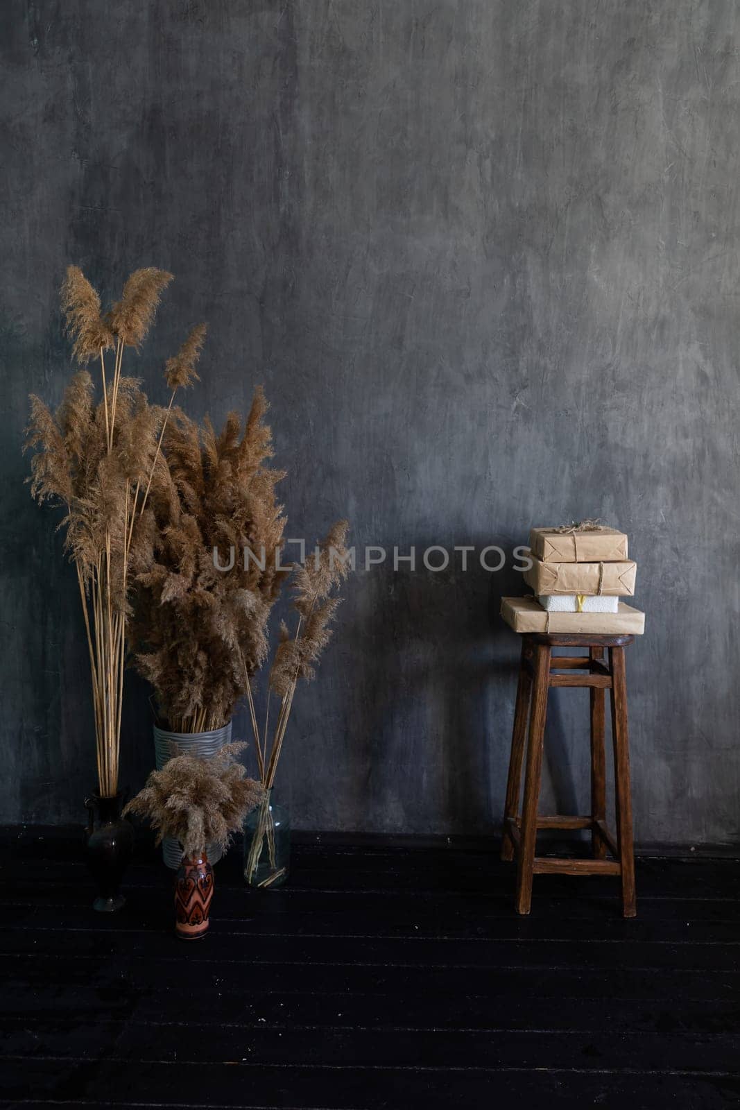 A vase with dried flowers and a chair with books in the interior of a dark gray room