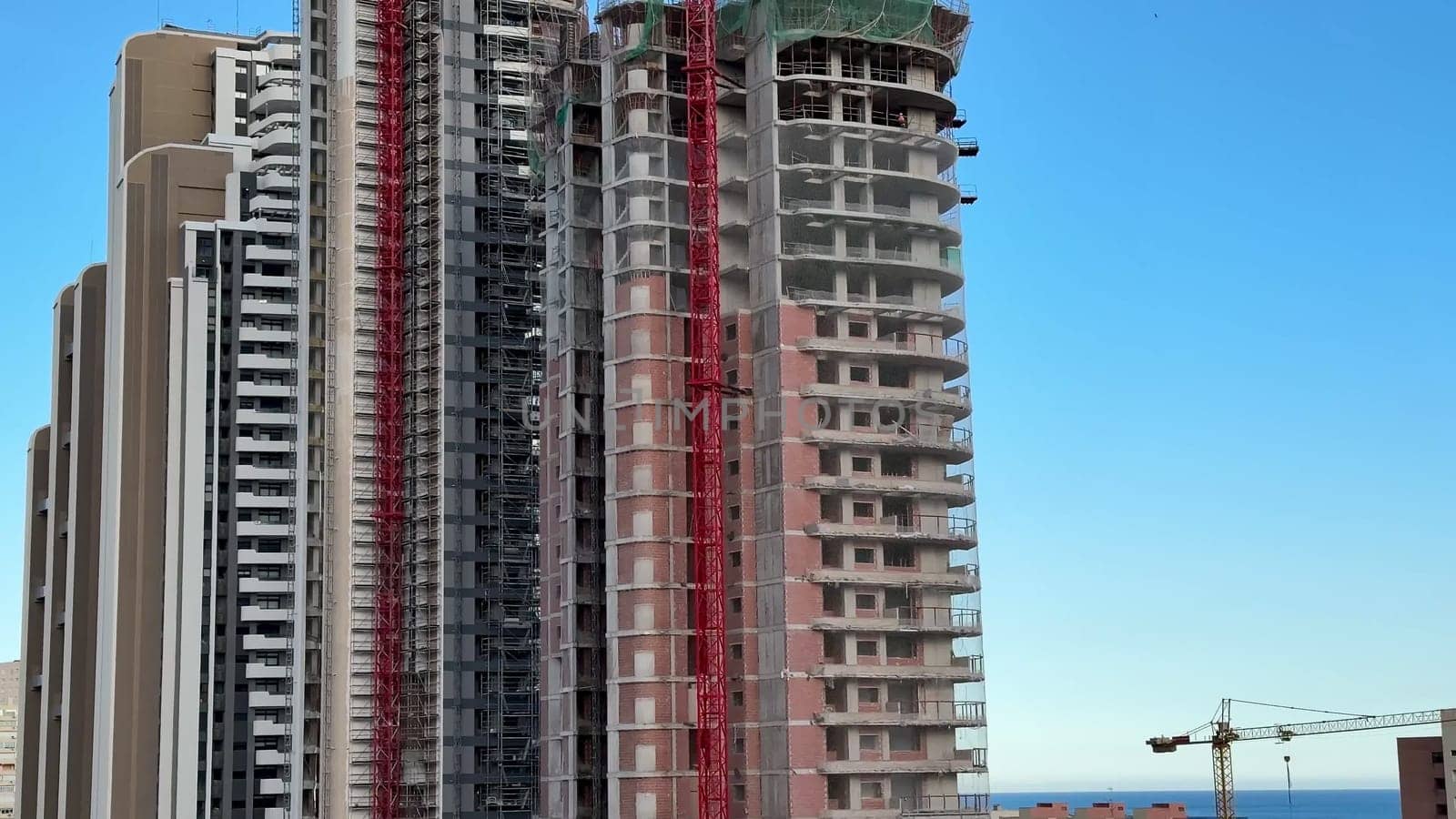 This vibrant view showcases highrise buildings under construction with cranes against a clear blue sky