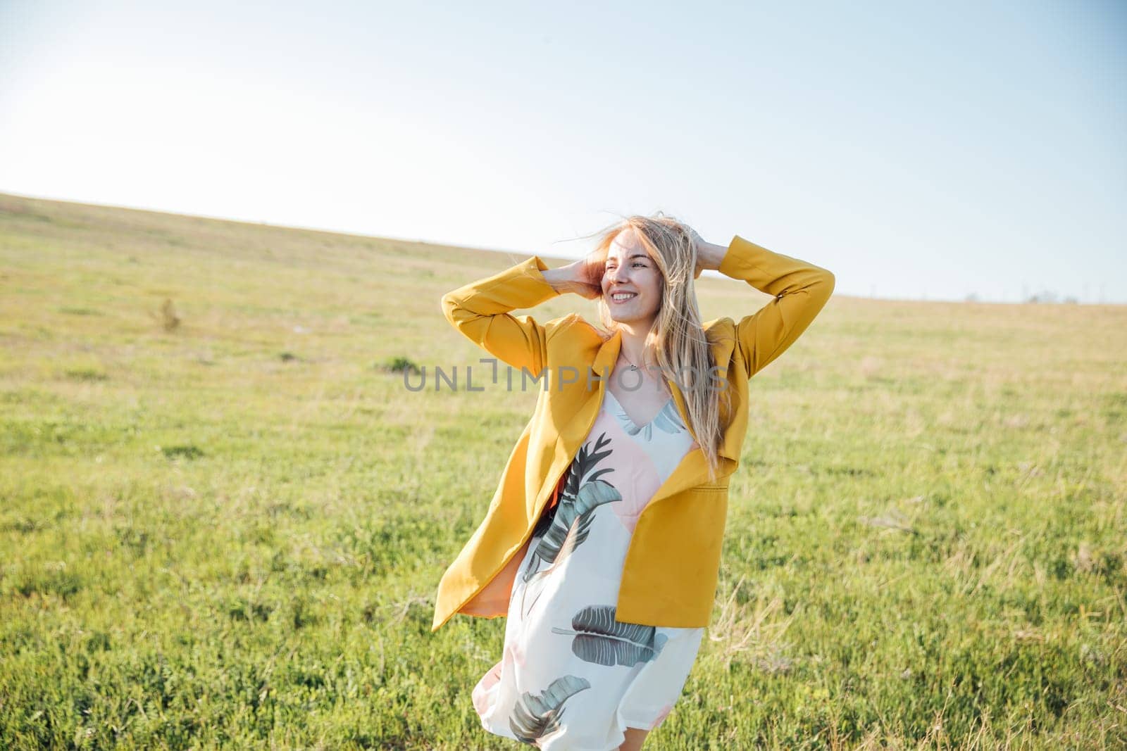 Woman in summer dress laughing at sunset on green field