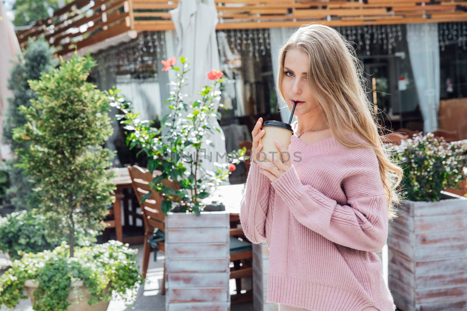 blonde woman in knitted pink dress drinking coffee cocktail