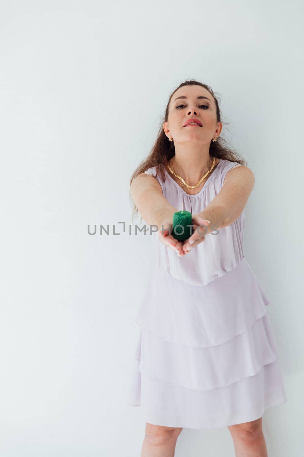 Brunette woman in summer dress holding out showing green candle