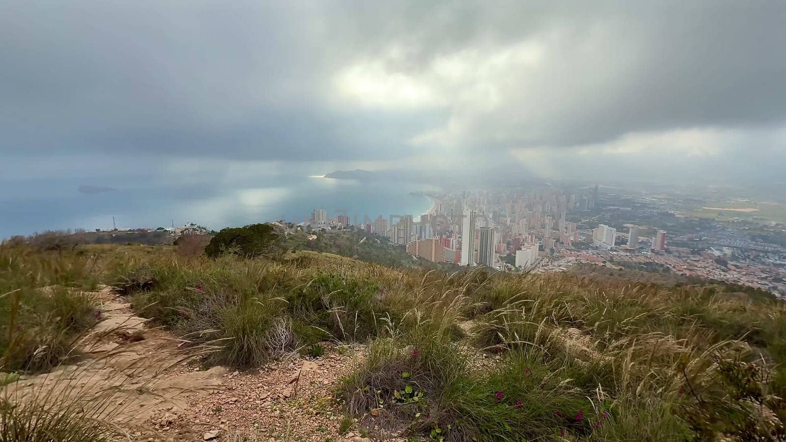 A breathtaking landscape beautifully showcasing a vibrant coastal city adorned with dramatic clouds and lush greenery