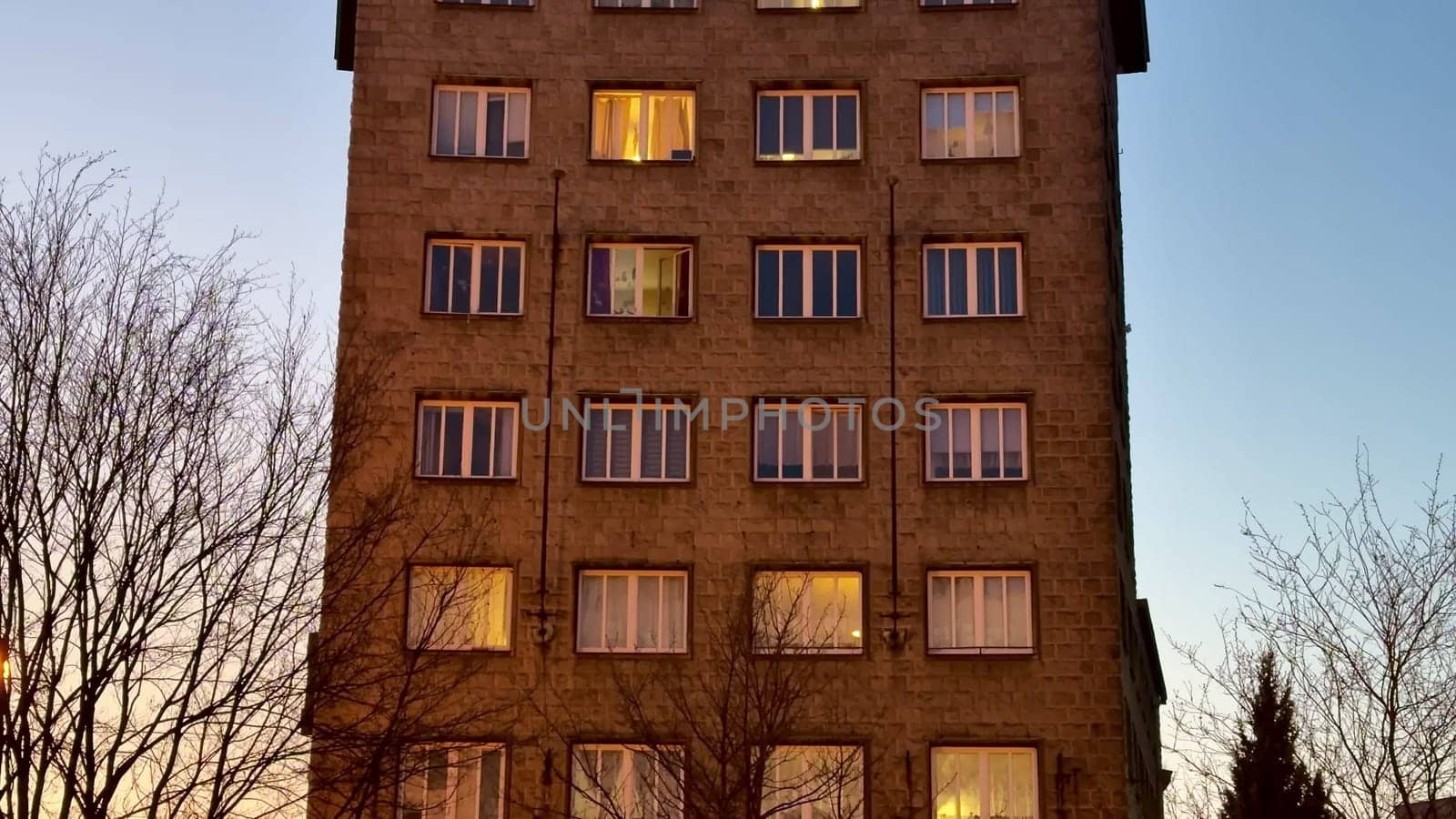 A captivating and striking view of a distinct and unique highrise building at dusk, featuring many illuminated windows