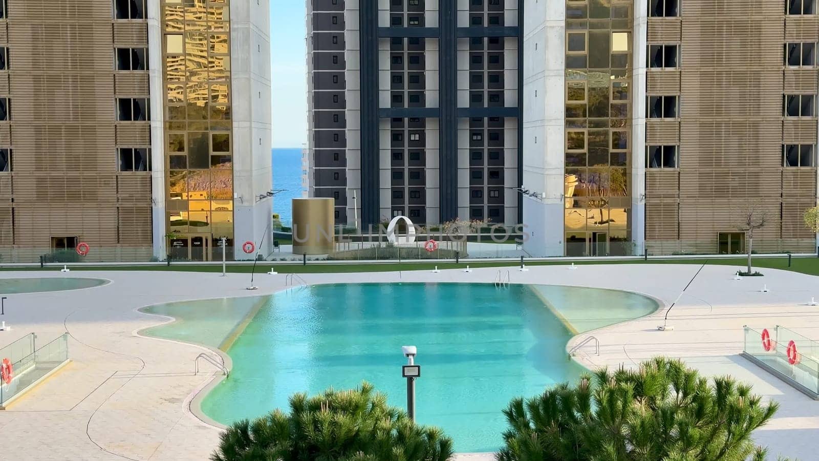 Stunning, intricately designed modern buildings reflect beautifully in the tranquil pool of a luxurious urban complex