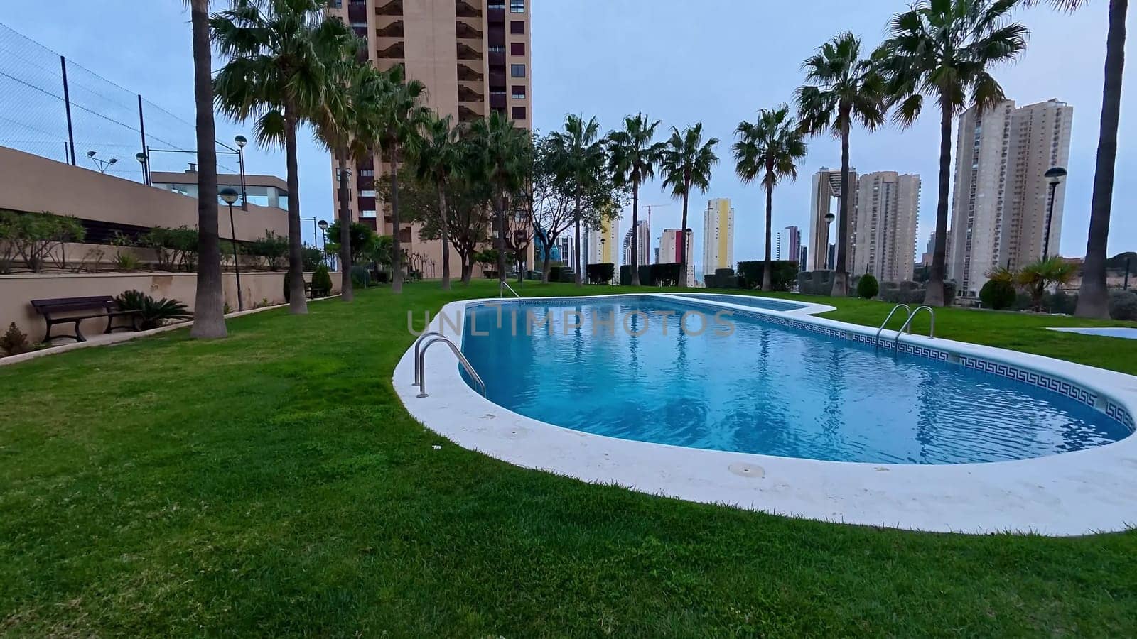 A beautiful pool area with tall palm trees and modern buildings, perfect for relaxation and leisure