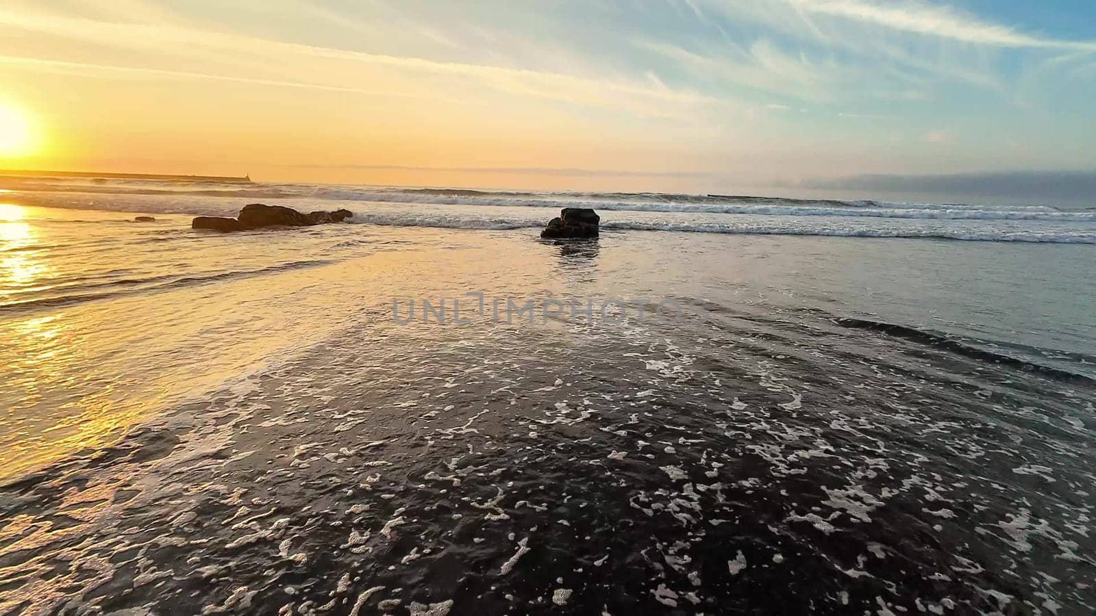 A serene and tranquil beach during sunset, showcasing gentle waves and beautiful soft golden hues illuminating the sky
