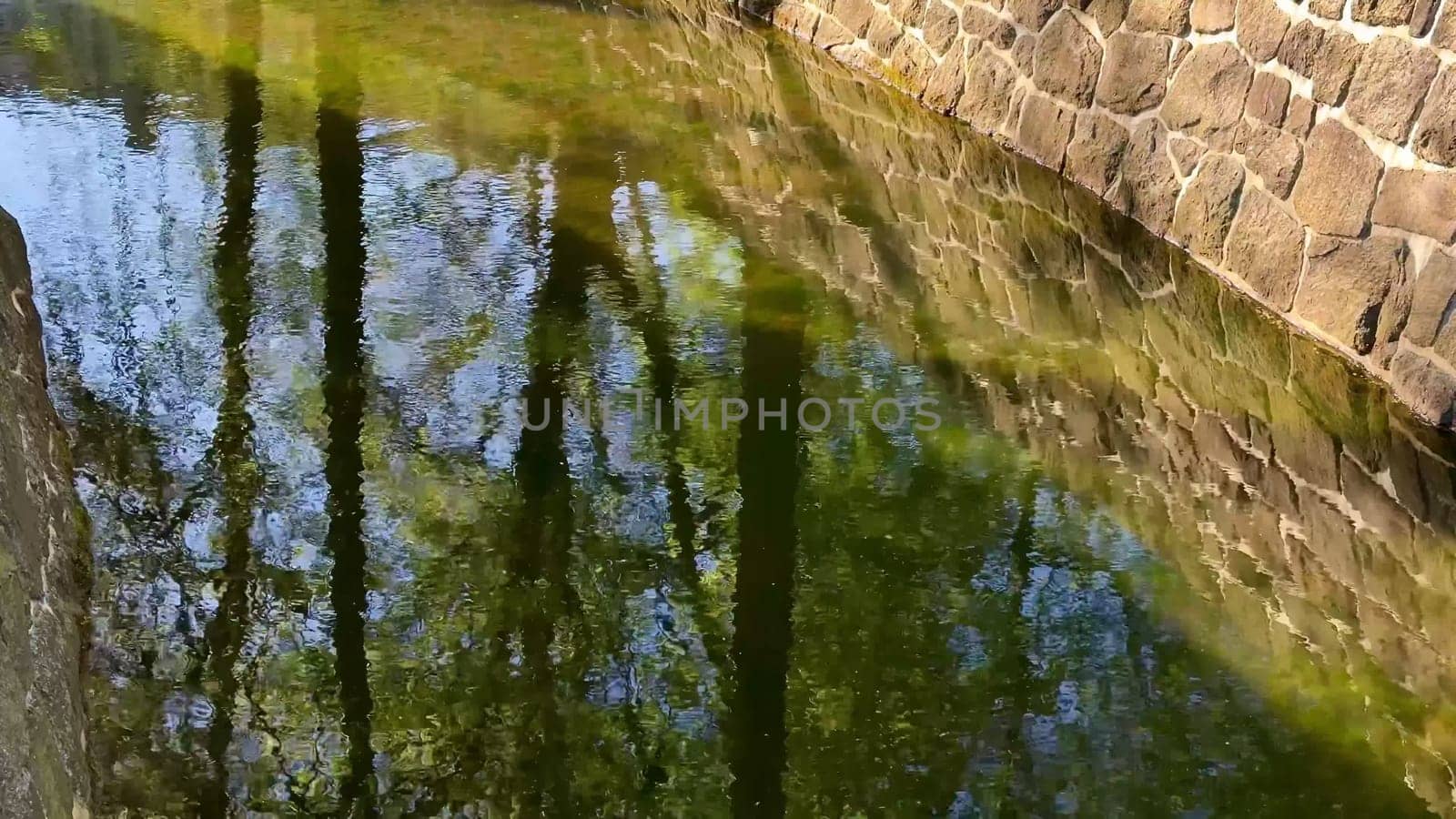 Enjoy a serene view of a flowing stream, a stone wall, and lush grass, creating a picturesque scene