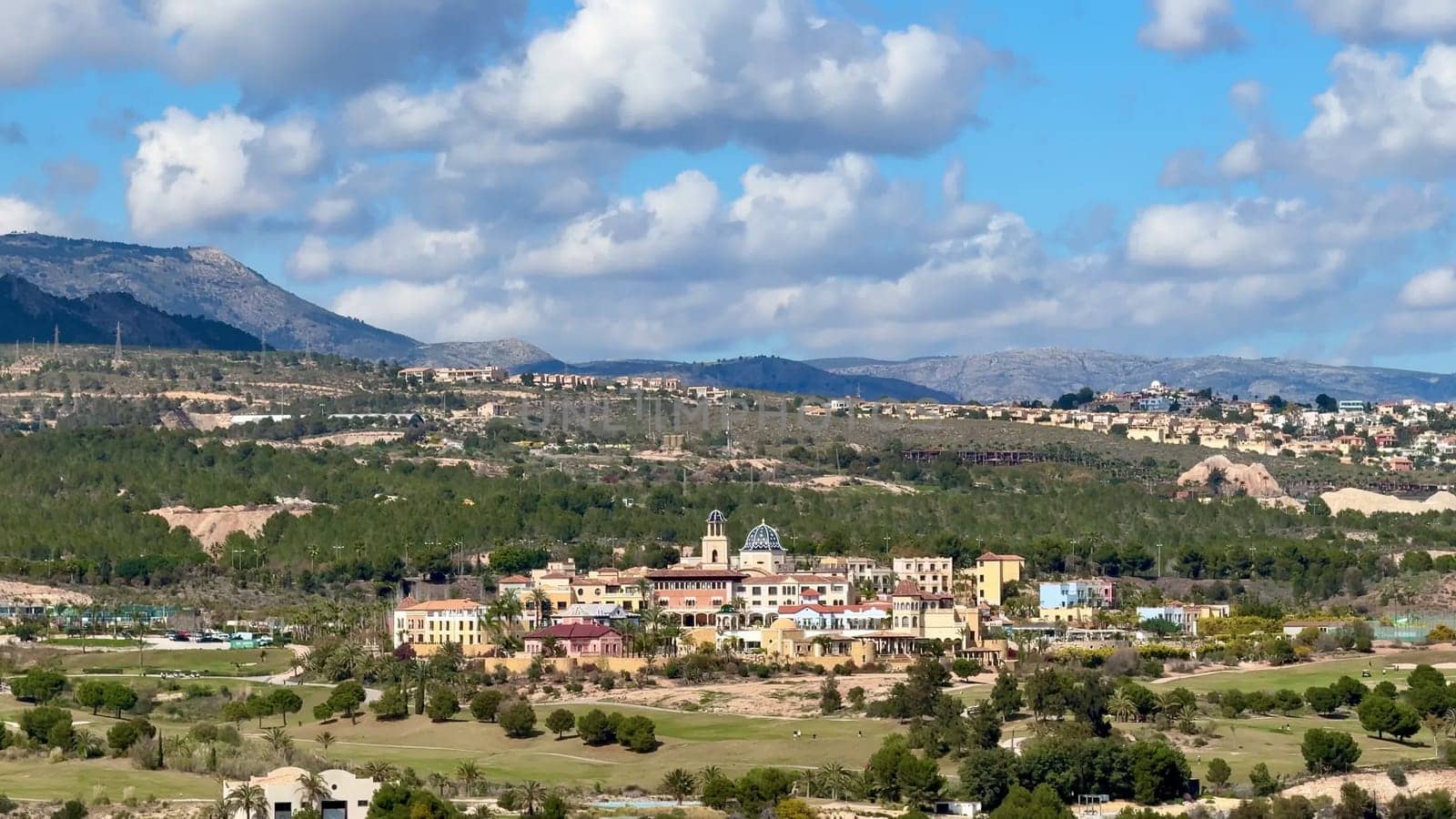 This picturesque landscape features a charming village among lush green fields and mountains, creating serenity