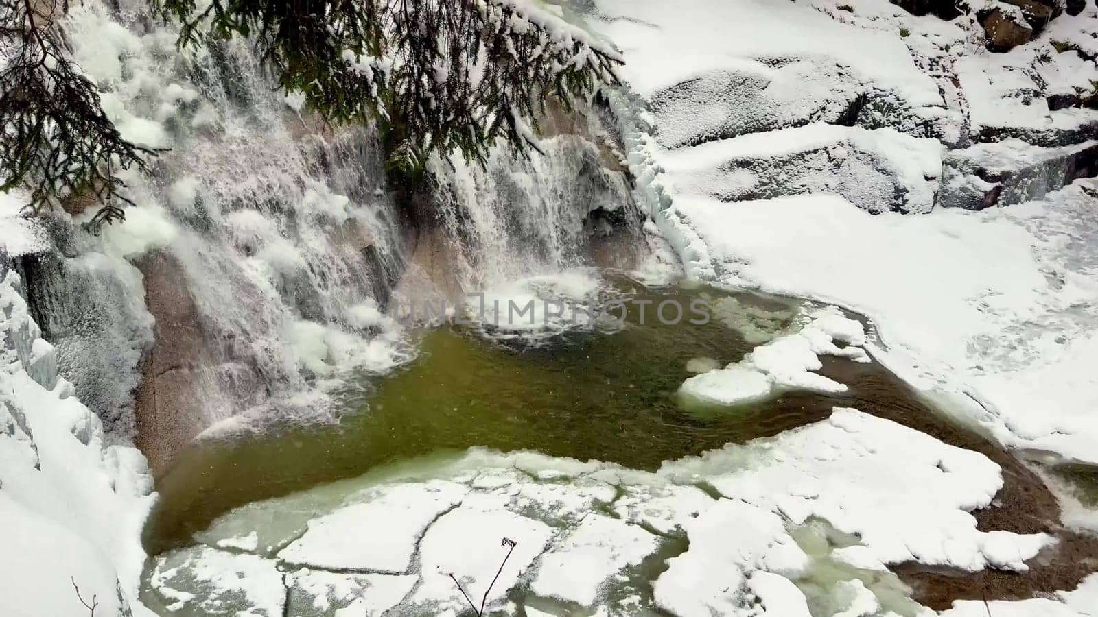Imagine a picturesque winter scene featuring a beautiful cascading waterfall surrounded by glistening snow and ice