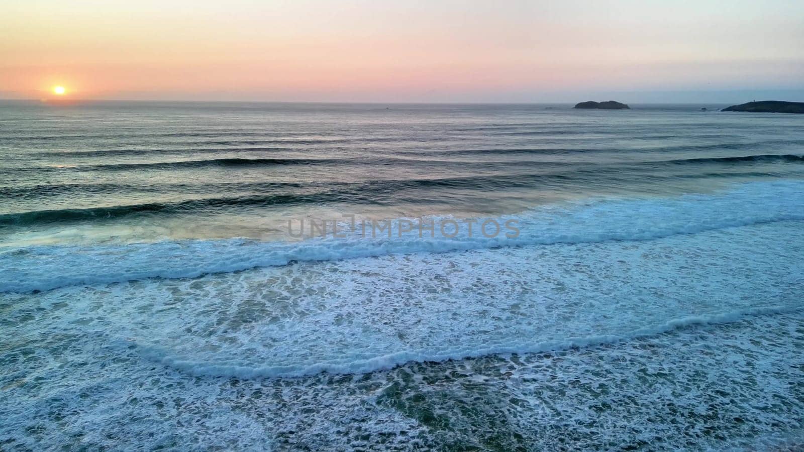 A stunning view of gentle ocean waves rolling gently onto a serene and tranquil beach as the sun sets beautifully