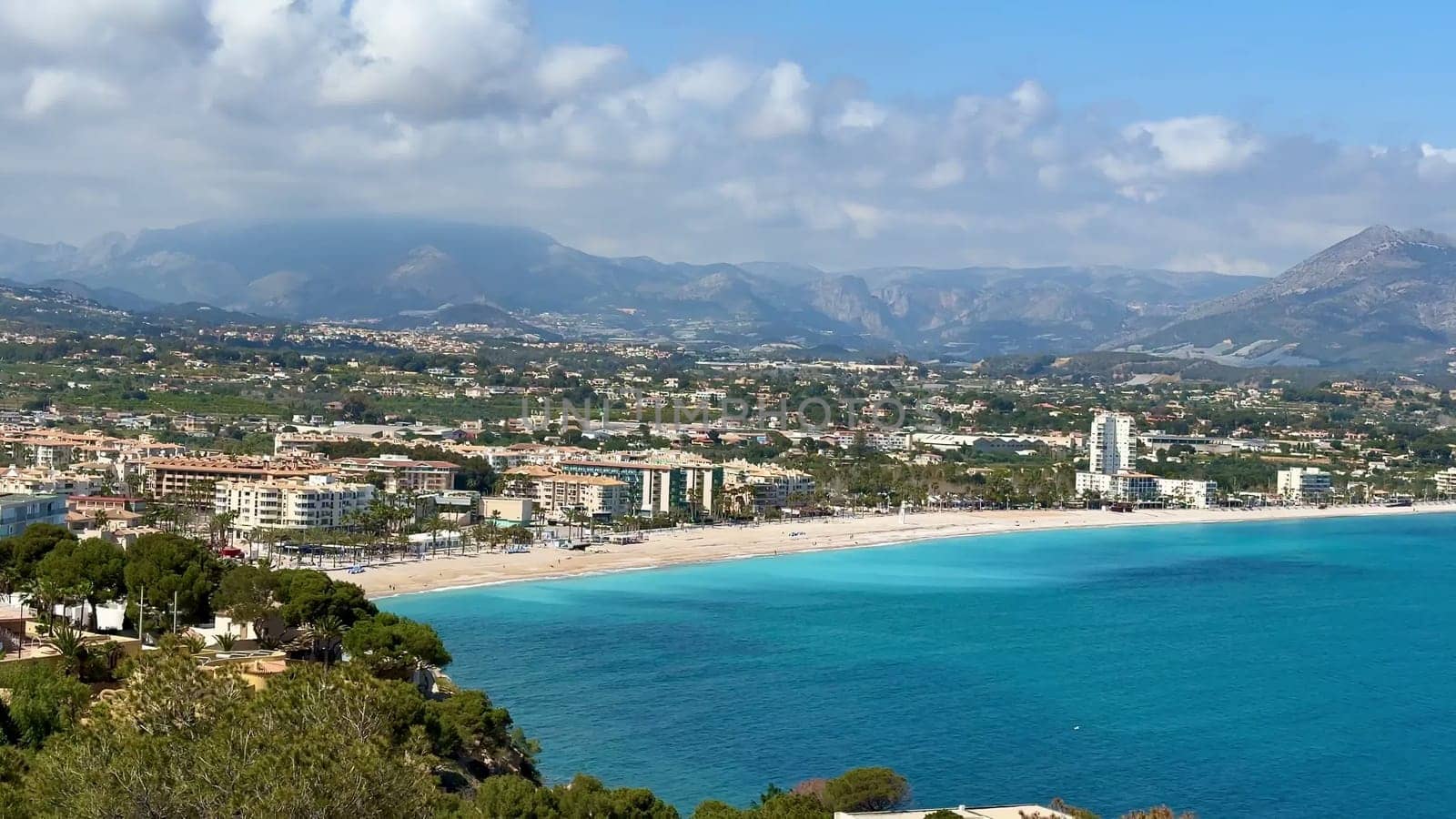 A stunning coastal landscape with turquoise waters, sandy beaches, and majestic mountains surrounding it