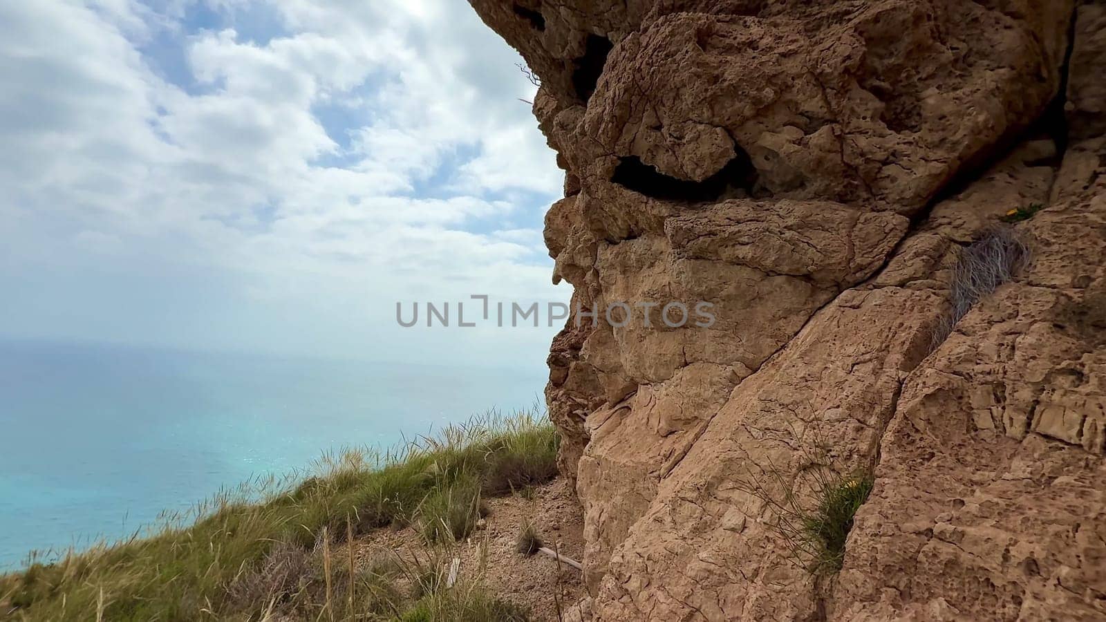 A breathtaking view of rugged rock formations overlooking a vibrant turquoise sea and a cloudy sky above