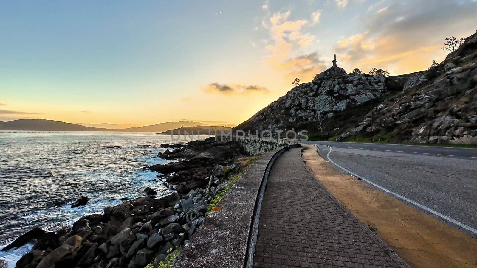 A breathtakingly beautiful coastal road at sunset, showcasing the vibrant ocean waves and rugged cliffs nearby
