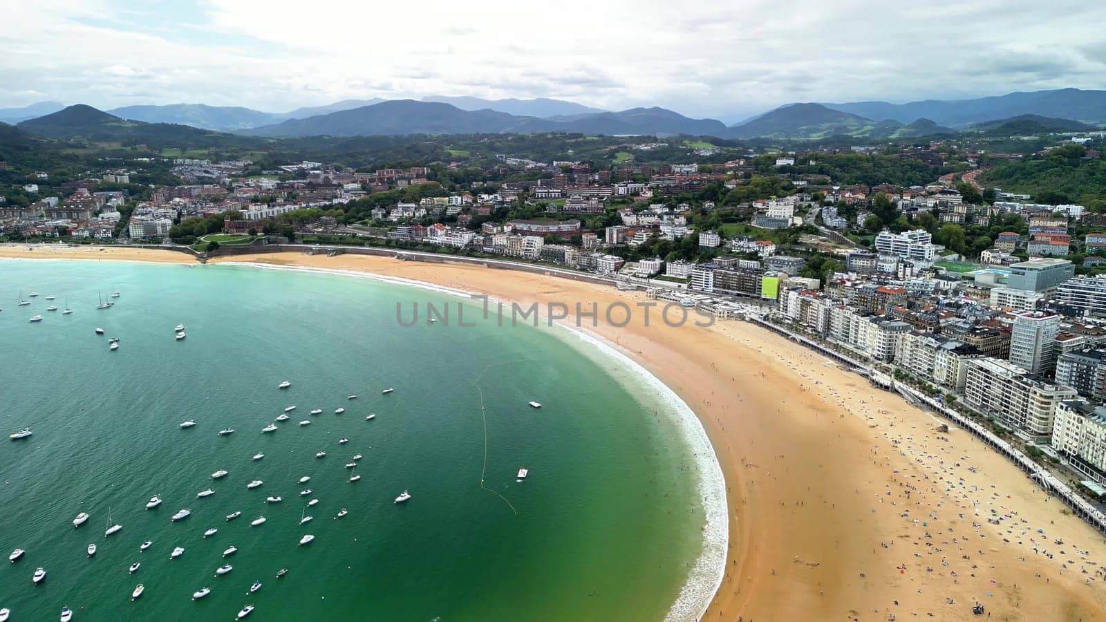 Enjoy stunning aerial views of a peaceful beach next to a busy city, perfect for relaxation during vacations
