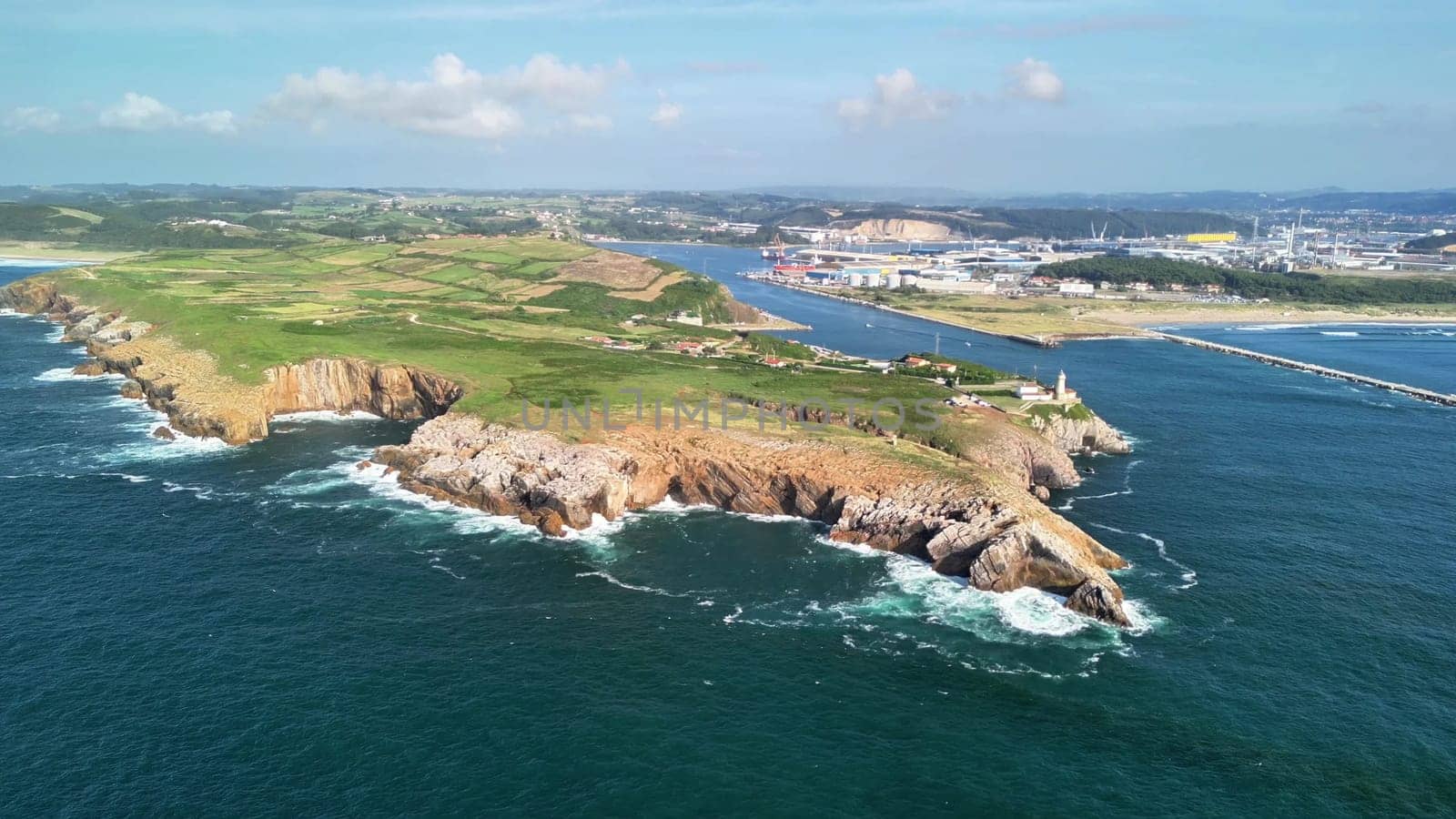 An aerial view captures stunning cliffs, lush greenery, and ocean waves, creating a breathtaking backdrop