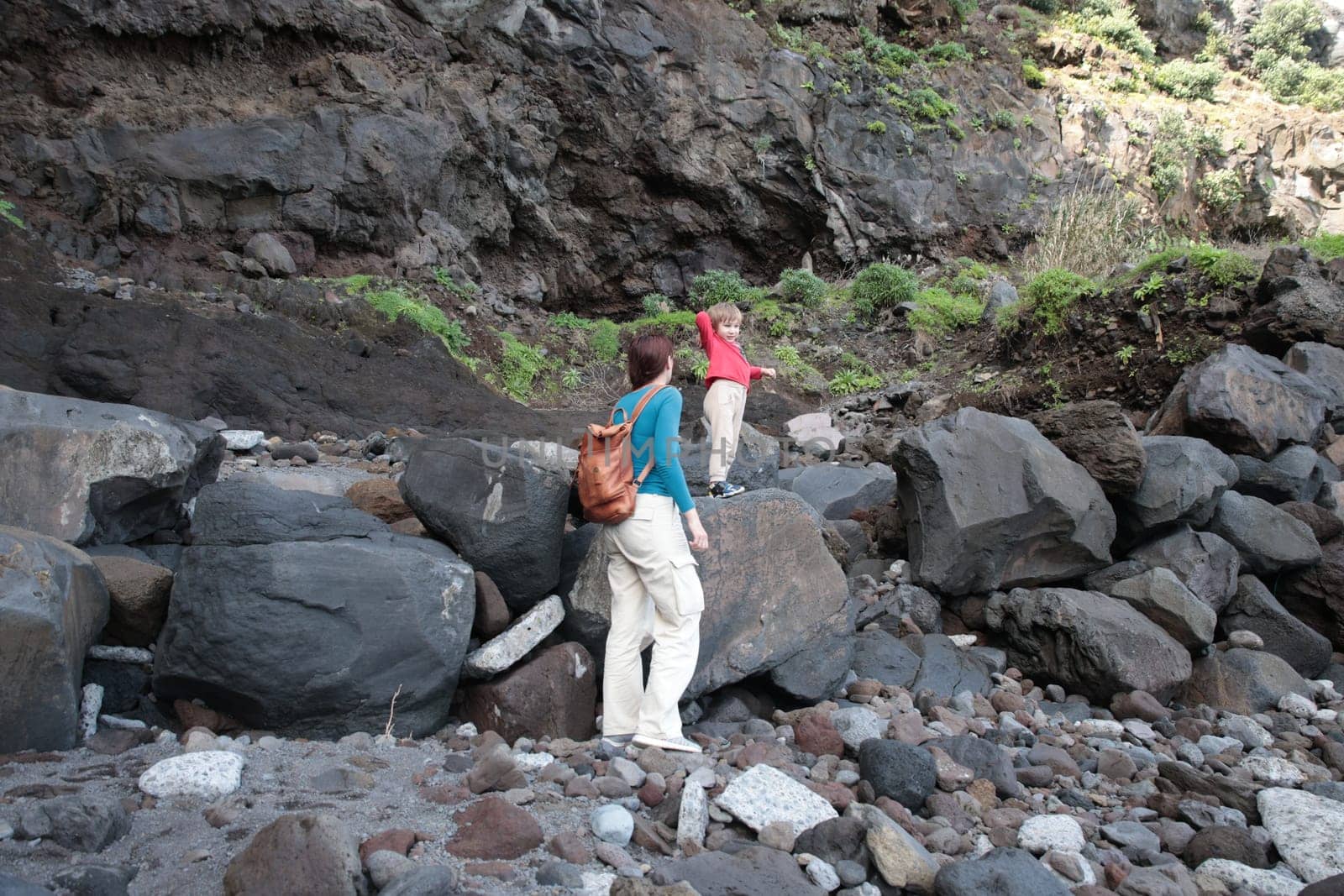 Mother and son exploring a rocky volcanic landscape, enjoying a hike amidst nature's rugged beauty