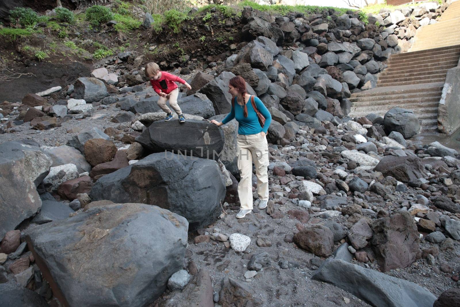 Mother and son navigating a rocky landscape, highlighting a sense of adventure and exploration in a natural setting