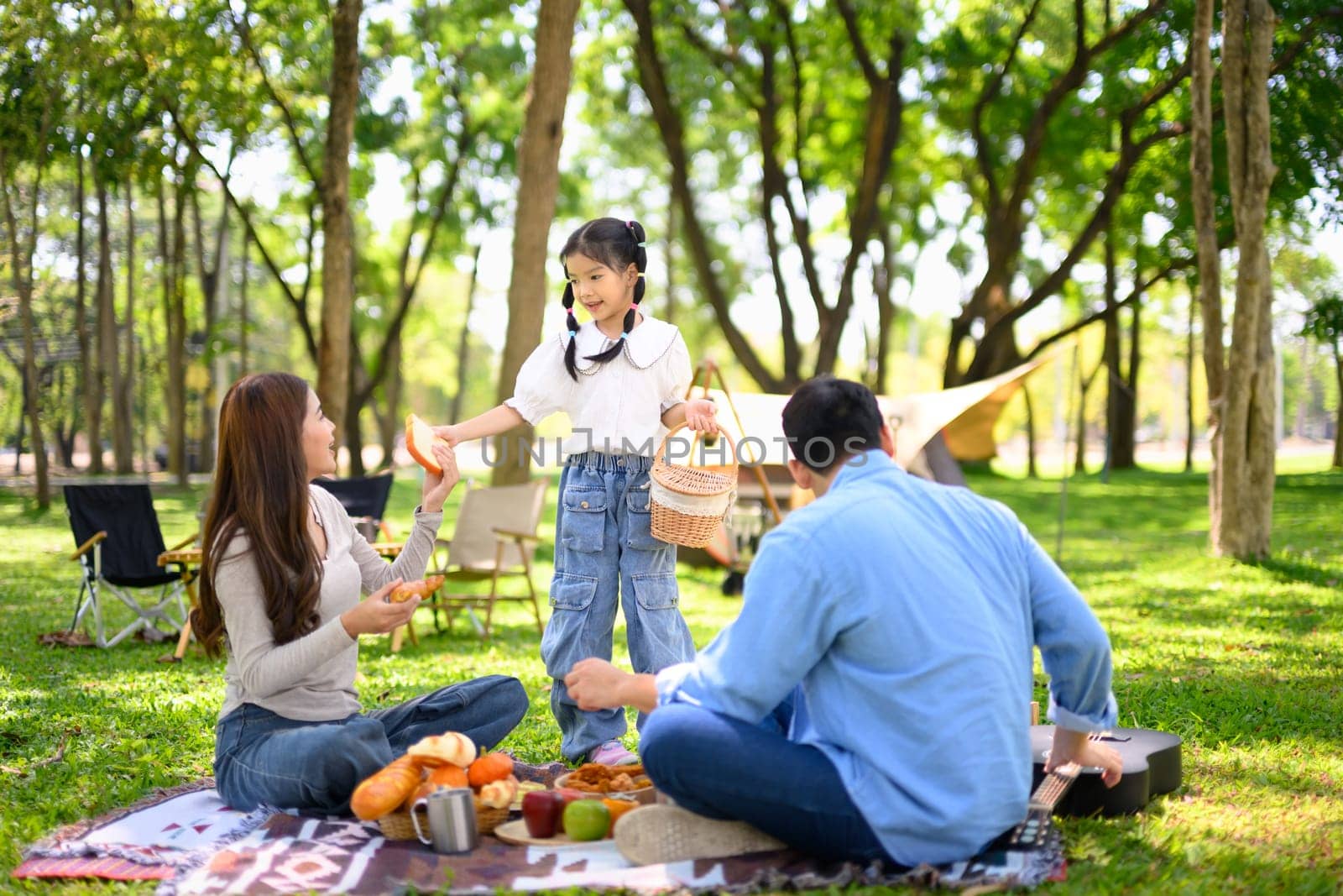 Cheerful family sharing food during a relaxing outdoor camping trip.
