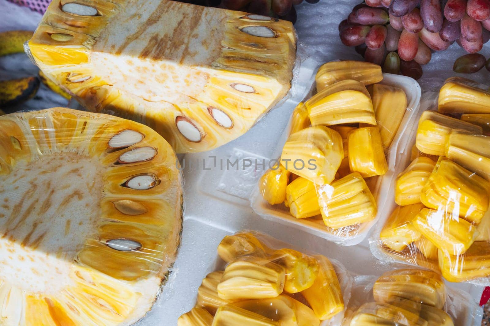 sliced fruit of a ripe yellow jackfruit on counter at the market. Tropical exotic fruits in Asia