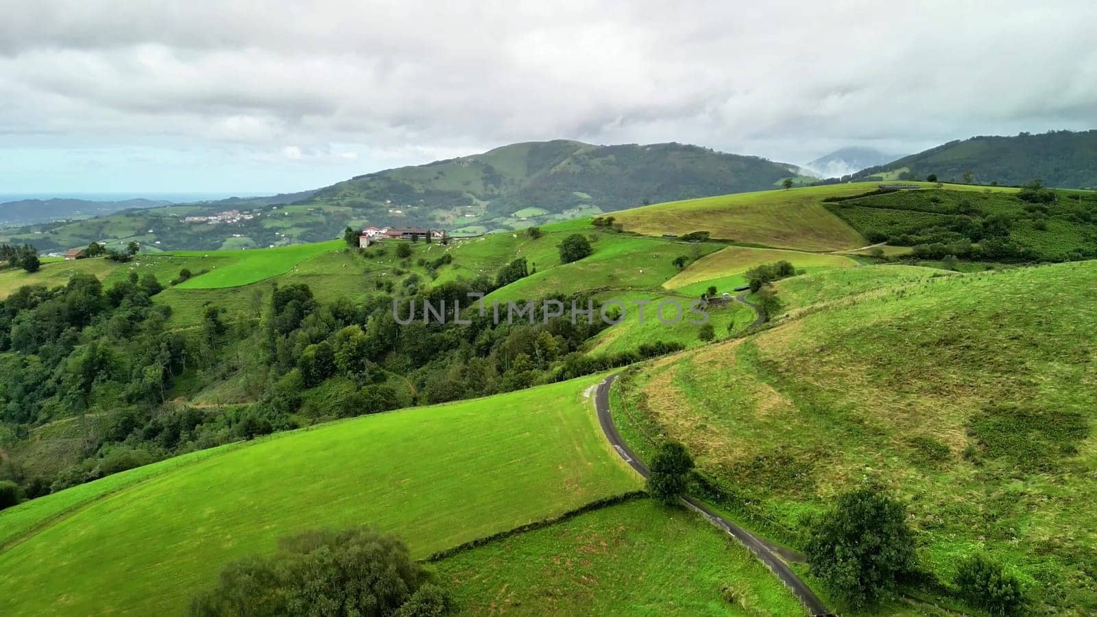 Gorgeous aerial view showcasing rolling green hills, meandering paths, all set beneath a beautifully cloudy sky