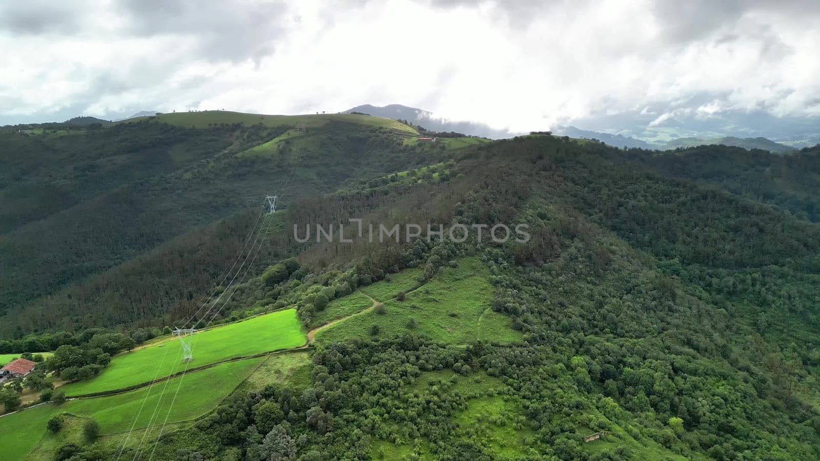 A breathtakingly majestic aerial landscape showcasing vibrant green fields and rolling hills beneath a cloudy sky