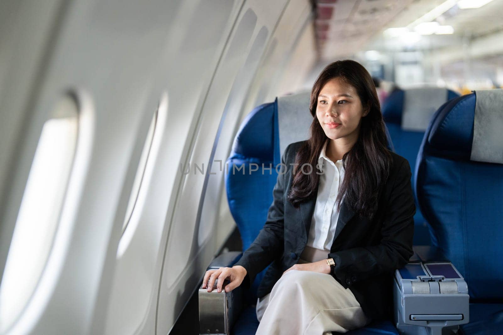 A young businesswoman sitting quietly on an airplane, reflecting on her journey while enjoying the flight.