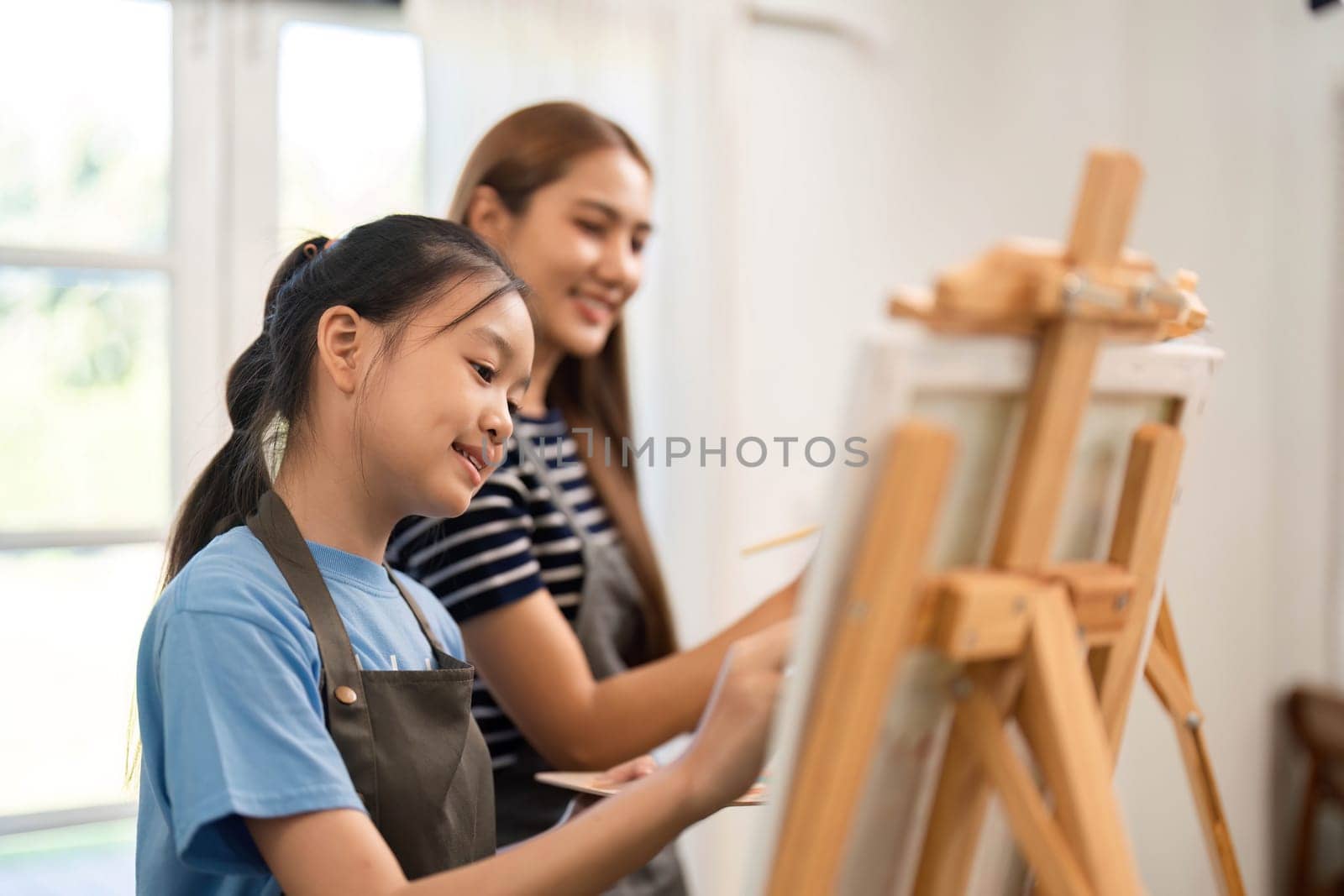 A mother and daughter happily creating art at home, sharing a special moment while painting and enjoying family time.