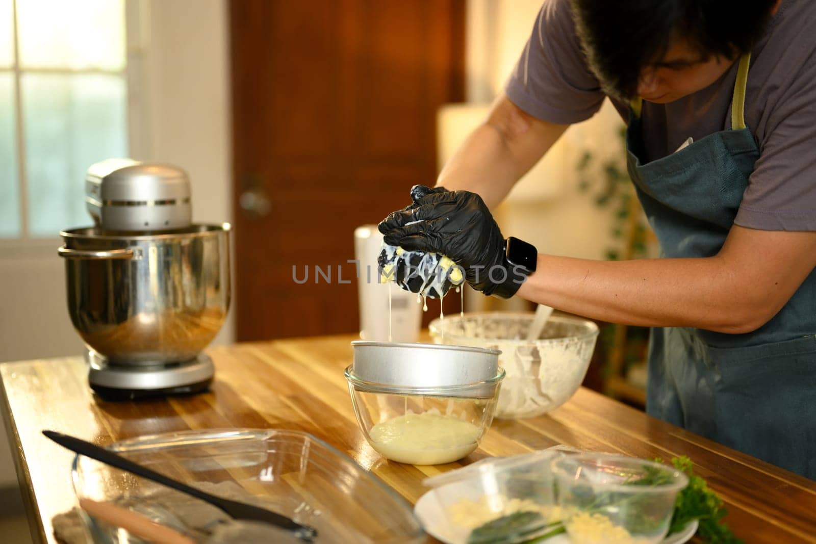 Close up of hands in gloves pressing butter to separate out liquid buttermilk.
